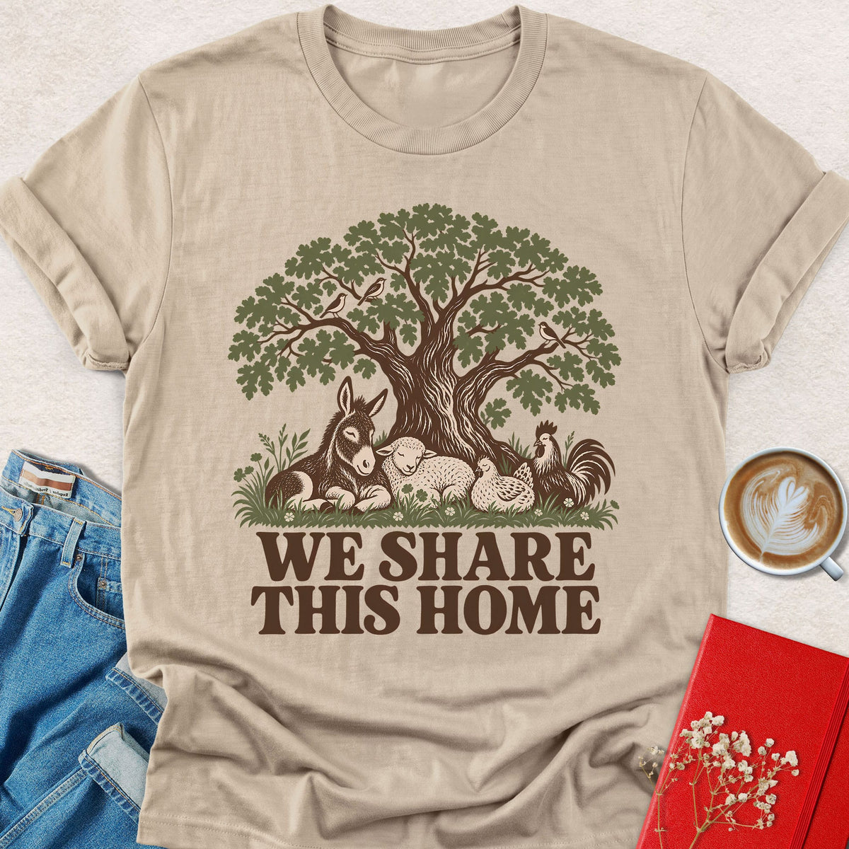 Sand crewneck T-shirt with tree-and-animals graphic and 'WE SHARE THIS HOME' text