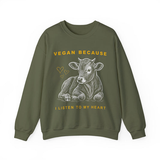 An military green crewneck sweatshirt featuring a graphic of a lying cow in gray, with yellow text reading 'VEGAN BECAUSE I LISTEN TO MY HEART' and small heart doodles.