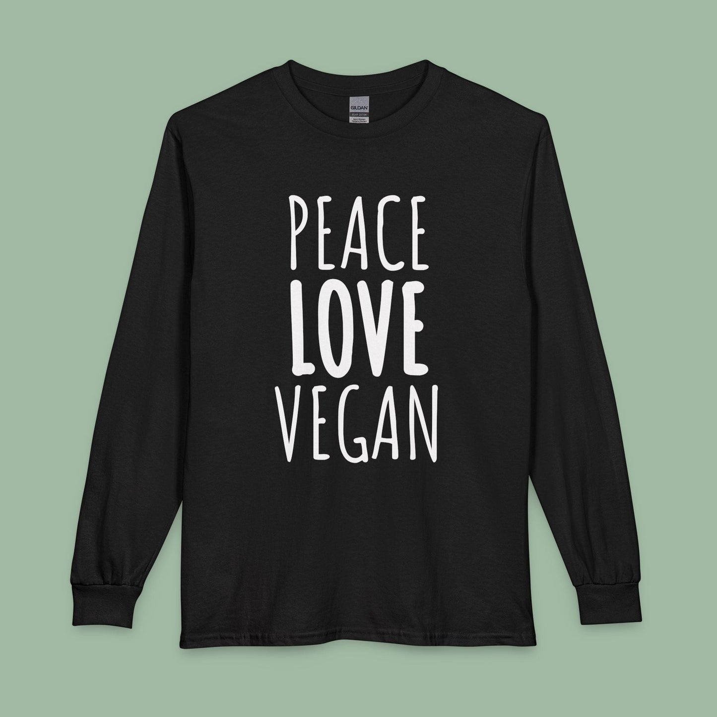 A black long-sleeve t-shirt with the words 'PEACE LOVE VEGAN' printed in white block letters on the front, displayed against a solid sage green background.