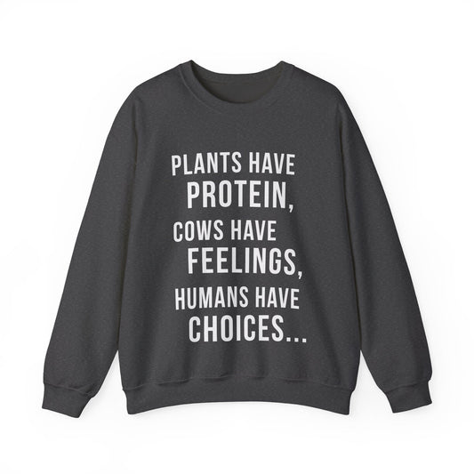 A dark heather gray crewneck sweatshirt with white text on the front that reads 'PLANTS HAVE PROTEIN, COWS HAVE FEELINGS, HUMANS HAVE CHOICES.