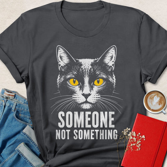 Charcoal cat graphic t-shirt with yellow-eyed cat face and SOMEONE NOT SOMETHING print